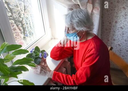 Le concept de santé, de sécurité et de pandémie du Covid-19 - une vieille femme solitaire séniée près de la fenêtre Banque D'Images