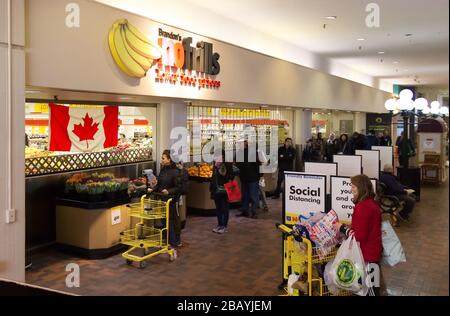 Vancouver, Canada - 20 mars 2020 : les gens s'unissent pour entrer dans le magasin sans frissons pratiquant l'éloignement social entre eux en raison de COVID-19. Banque D'Images