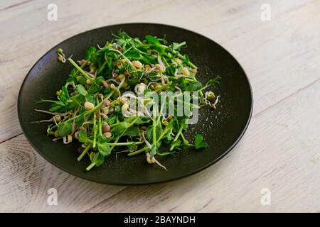 Gros plan de salade végétalienne saine faite de petits pois microverts et de haricots moulus sur fond de bois. Banque D'Images