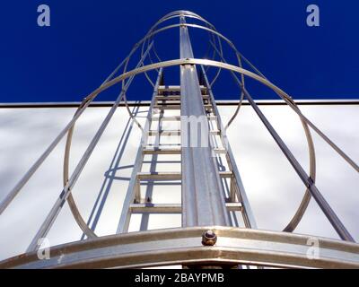 échelle d'accès au toit en aluminium et cage de sécurité. point de vue décroissant. mur en béton blanc. barreaux et barres de sécurité verticales. architecture et technologie Banque D'Images