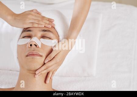 Esthéticienne massant le visage du client du salon de spa et appliquant des taches sous les yeux et un autocollant d'enlèvement de tête noire pour le nez Banque D'Images