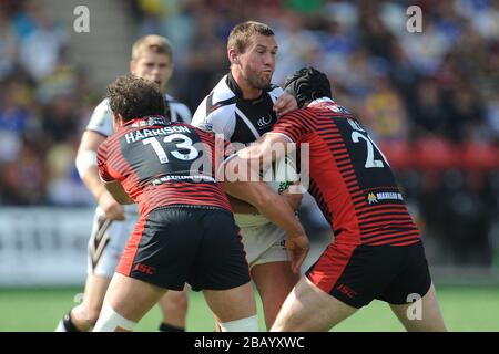 Steve Pickersgill de Widnes Vikings est traité par Ben Harrison de Warrington Wolves (à gauche) et Chris Hill (à droite) Banque D'Images