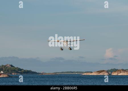 Un hydravion Cessna 172 Skyhawk jaune et blanc qui s'envole parmi les îles de l'archipel de Kragerø, sur la côte sud de la Norvège. Banque D'Images