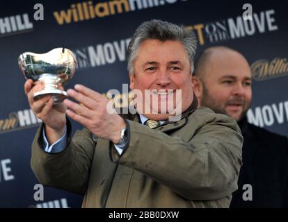 L'entraîneur Paul Nicholls célèbre avec son trophée après avoir remporté le William Hill King George VI Chase avec Silviniaco Conti Banque D'Images