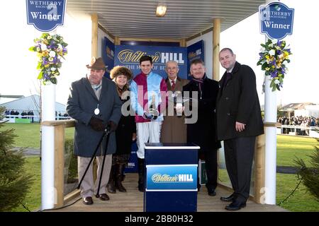 Les liens gagnants de Cloudy aussi, y compris jockey Jonathan Angleterre (troisième à gauche), après la victoire dans le William Hill Rowland Meyrick handicap Chase Banque D'Images