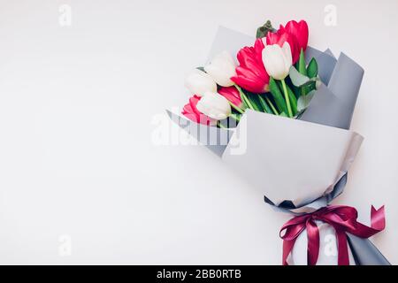 Cadeau présent pour la fête des mères. Fleurs printanières pour la journée internationale de la femme. Bouquet de tulipes blanches et roses. Banque D'Images