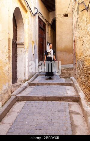 Fes, Maroc: Jeune femme voilée marchant dans la Médina Banque D'Images