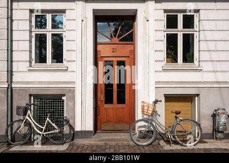 Vélos penchant contre un mur à côté d'une porte de maison Banque D'Images