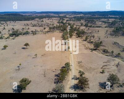 Aérien d'une route de campagne non scellée passant par la sécheresse a affecté la région de pâturage des bovins près du mont Perry Queensland Australie Banque D'Images