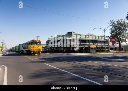 Pacific National Freight train qui passe devant un hôtel de style queenslander à Rockhampton Queensland Australie Banque D'Images