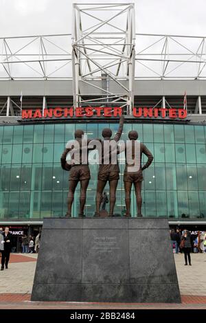 On peut voir une vue générale sur Old Trafford, la statue de la Trinité unie des anciens joueurs George Best, Denis Law et Bobby Charlton Banque D'Images