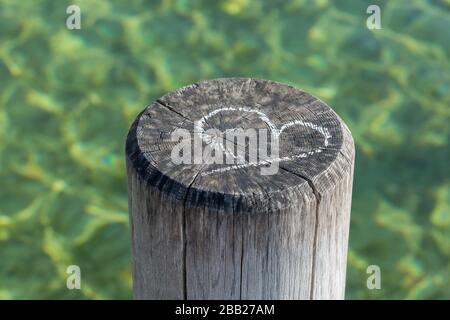 Craie dessin d'un symbole de coeur sur une pile en bois d'une jetée. Dans l'arrière-plan de l'eau verte. Concept pour l'amour, le mariage, être ensemble, la Saint Valentin. Banque D'Images