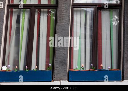 Tulipes artificielles en plastique dans des pots sur un seuil de fenêtre à Amsterdam, Pays-Bas. Banque D'Images