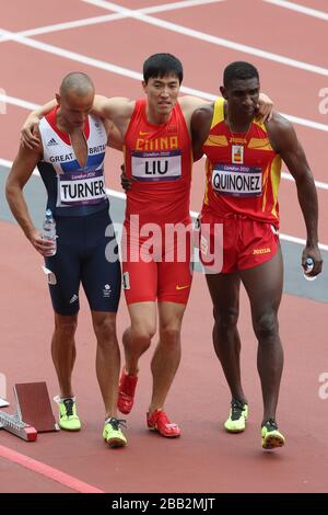 Liu Xiang de la Chine est aidé de la piste par Andrew Turner (à gauche) de Grande-Bretagne et Jackson Quinonez (à droite) d'Espagne après avoir frappé le premier obstacle et se blessant tout en participant à la Heat 6 des 110 m haies hommes Round 1 au stade olympique de Londres. Banque D'Images