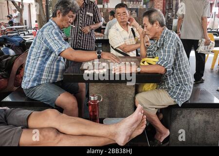 Les hommes singapouriens âgés qui passent leur temps en jouant une sorte d'échecs chinois sur la place Kreta Ayer, Chinatown, Singapour Banque D'Images