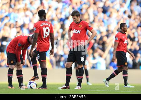 Wayne Rooney (à gauche), Danny Welbeck (au centre) et Michael Carrick (deuxième à droite) ont été déjectés et attendent de reprendre le match après que Sergio Aguero (pas sur la photo) de Manchester City ait marqué l'objectif d'ouverture de son équipe Banque D'Images