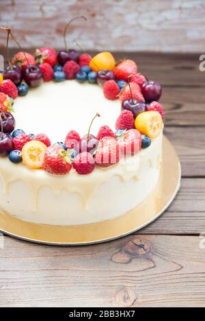 Cheesecake au chocolat blanc, baies fraîches, fraises, cerises, bleuets et framboises sur fond de bois. Dessert d'été. Banque D'Images