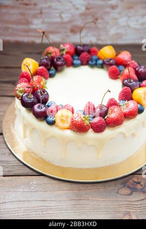 Cheesecake au chocolat blanc, baies fraîches, fraises, cerises, bleuets et framboises sur fond de bois. Dessert d'été. Banque D'Images