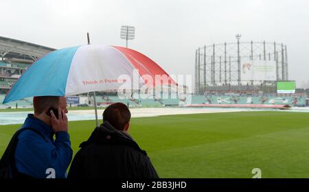 Deux fans s'abritent sous un parapluie car les couvertures de pluie se trouvent sur le terrain le quatrième jour du cinquième test Ashes à l'ovale Kia Banque D'Images