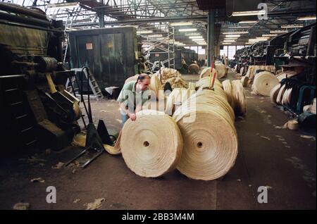 Un travailleur roulant une balle circulaire de jute à l'usine de Tay Spinners à Dundee, en Écosse. Cette usine était la dernière usine de filature de jute en Europe lors de sa fermeture pour la dernière fois en 1998. La ville de Dundee avait été célèbre tout au long de l'histoire pour les trois 'JS' - jute, confiture et journalisme. Banque D'Images