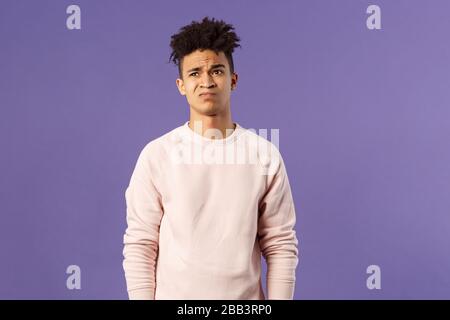 Portrait de jeune homme réticent et mécontent ayant hésité, peu disposé à aller quelque part, n'ont pas d'intérêt, grimaçant et regardant loin Banque D'Images