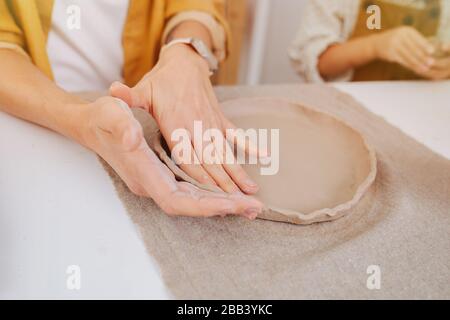 gros plan sur les mains des femmes, elle modélise une plaque, sur le fond des mains de l'enfant avec de l'argile Banque D'Images