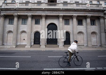 Un cycliste passe devant la Banque d'Angleterre dans la ville de Londres alors que le Royaume-Uni continue de se maintenir en place pour aider à freiner la propagation du coronavirus. Banque D'Images