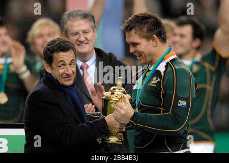 John Smit (Afrique du Sud, capitaine, à droite) prend le trophée Webb Ellis d'un président français à la recherche étriquée Nicolas Sarkozy (à gauche). Regardé par incomin Banque D'Images