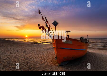 Bateau de pêche coloré sur une plage de sable durant un beau coucher de soleil Banque D'Images