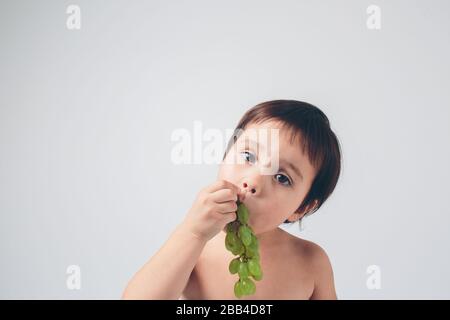 bébé tenant du raisin, gros plan. concept. isolé sur blanc. Banque D'Images