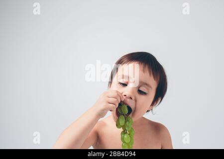 bébé tenant du raisin, gros plan. concept. isolé sur blanc. Banque D'Images