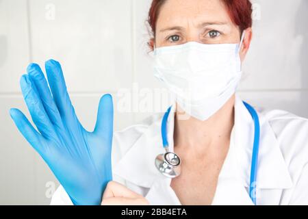 Gros plan portrait d'une infirmière ou d'un médecin mettant sur ses gants chirurgicaux pour se protéger Banque D'Images