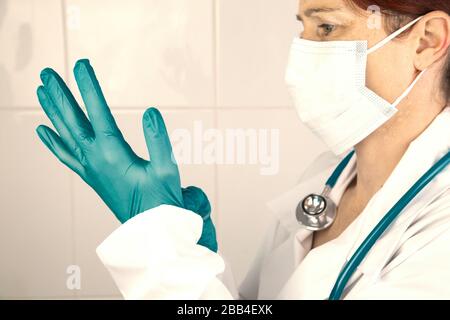 Vue latérale d'une infirmière ou d'un médecin mettant ses gants chirurgicaux pour se protéger Banque D'Images