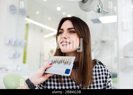 Le dentiste sélectionne une nuance de dents pour le patient. Concept de soins dentaires professionnels Banque D'Images