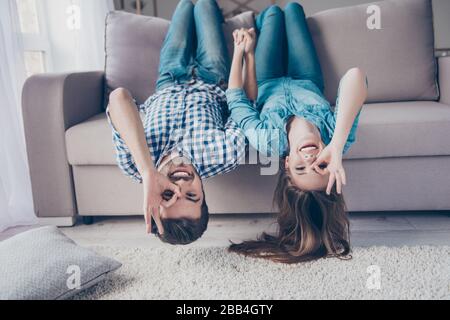 Drôle couple avec lunettes gestuelle est allongé à l'envers sur le canapé à la maison. Ils sont si joyeux, s'amuser ensemble, aller fou, frère et sœur Banque D'Images