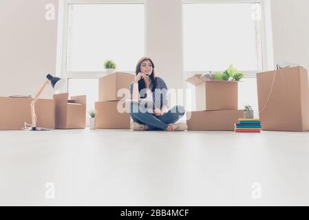 Photo basse angle de la jeune femme brunette dans un appartement moderne clair, à la recherche et à la rêve, la planification comment elle organisera l'espace dans un nouvel appartement Banque D'Images