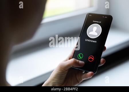 femme tenant un téléphone mobile avec un appel entrant provenant d'un appelant inconnu Banque D'Images