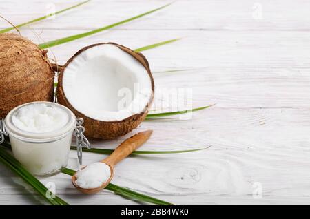 L'huile de noix de coco dans un bocal en verre hermétique et cuillère en bois blanc sur les plaques tableau Banque D'Images