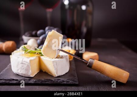 Fromage camembert brie sur le plateau, deux verres et une bouteille de vin rouge. Banque D'Images