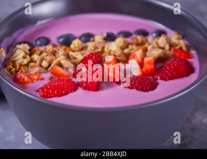 Bol à smoothie avec baies et muesli sur la table grise Banque D'Images