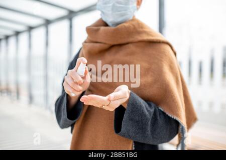 Femme pulvérisant un antiseptique sur les mains à l'extérieur, protégeant de l'infection virale. Concept d'hygiène pendant l'épidémie de Coronavirus Banque D'Images