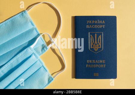 Passeport Forein de l'Ukraine près de deux masques médicaux bleu clair sur les milieux jaunes lumineux contre le virus covid-2019. Concept de soins de santé, arrêt Banque D'Images