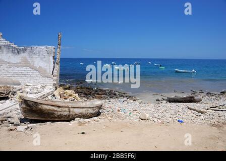 Vieux canoë en bois de pêcheur sur la plage sale. Maison détruite sur la gauche. Banque D'Images