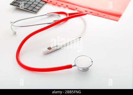 Rendez-vous avec un médecin. Thermomètre, stéthoscope rouge et documents médicaux sur le lieu de travail des médecins au bureau de la clinique. Concept médecine soins de santé Banque D'Images