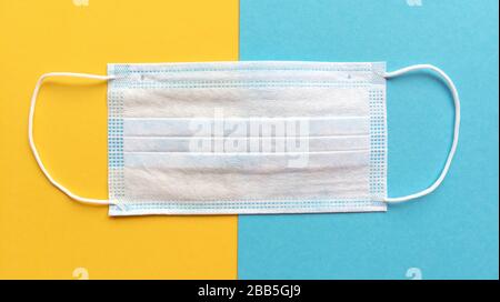 Masque médical sur fond jaune et bleu. Pose plate simple. Concept médical. Photo de stock. Banque D'Images