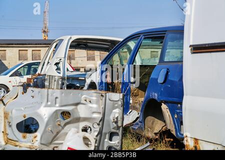 vieux cadre gris voiture démontée voiture avec des pièces rouillées dans la rue près de la clôture. Banque D'Images