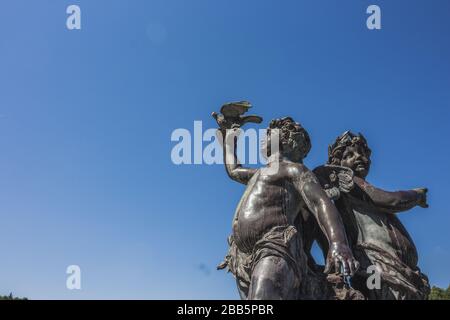 Statue des anges et ciel bleu, Sculpture de cupid, la statue du petit ange tient un oiseau dans sa main. Banque D'Images