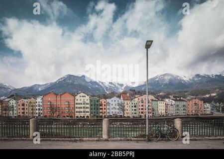 Vue sur le centre-ville historique d'Innsbruck avec des maisons colorées le long de la rivière Inn et de célèbres sommets de montagne autrichiens en arrière-plan avec un vélo, Banque D'Images