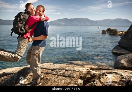 Mid-adult woman hugging excité son mec à côté de lac magnifique. Banque D'Images