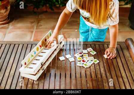 Mains d'un enfant à l'aide d'un jouet en bois pour comparer des images, utilisés dans les pédagogies alternatives, dans l'arrière-cour de sa maison. Banque D'Images